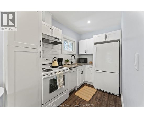 A white kitchen with a refrigerator, oven, and microwave.