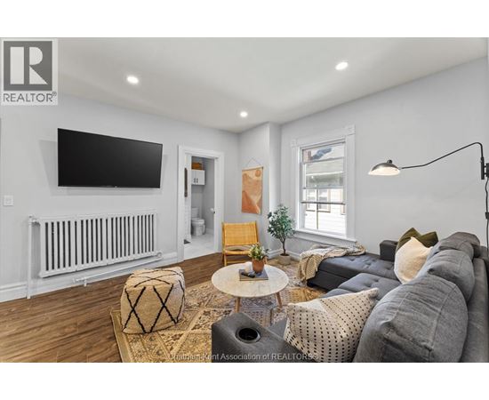 A living room with a grey couch, a coffee table, and a flat screen TV mounted on the wall.