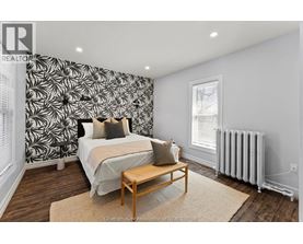 A bedroom with a patterned wallpaper and a bed with a wooden frame.