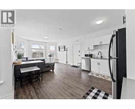 A modern kitchen with white cabinets and a black refrigerator.