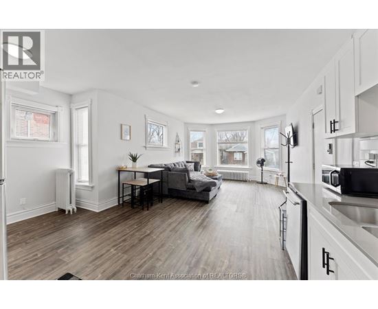 A well-lit, spacious kitchen and living room with hardwood floors and white walls.