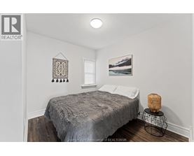 A bedroom with a bed, a basket, and a picture on the wall.