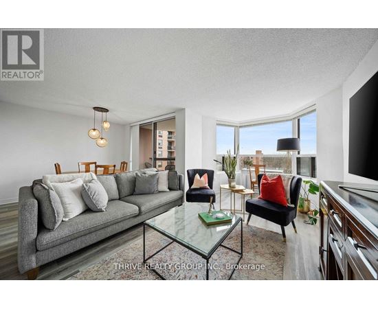 A well-lit living room with a grey couch and a glass coffee table.