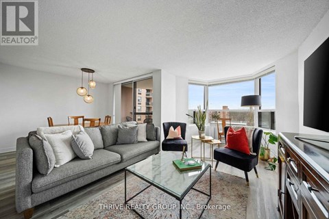 A well-lit living room with a grey couch and a glass coffee table.