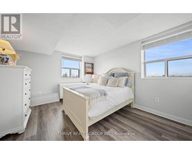 A bedroom with a large bed, a dresser, and a window overlooking the ocean.