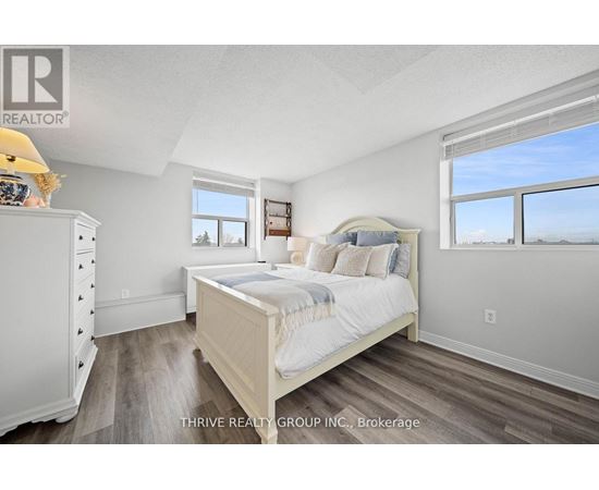 A bedroom with a large bed, a dresser, and a window overlooking the ocean.