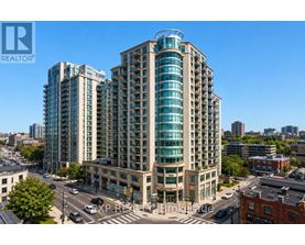 A tall building with a glass facade stands in the middle of a city street.