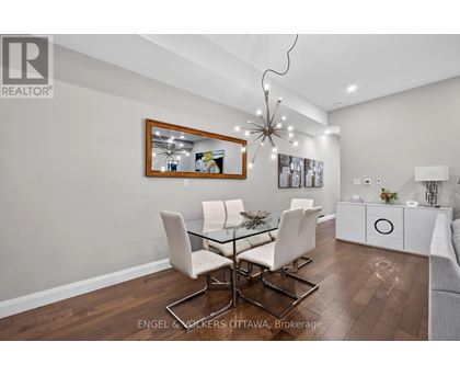 A modern dining room with a glass table and white chairs.
