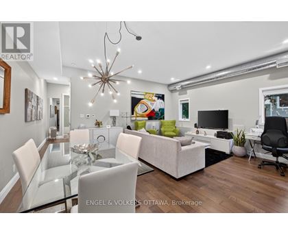 A modern living room with a glass dining table and white chairs.
