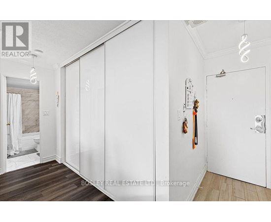 A white bedroom with a large closet and a bed in the background.