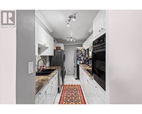 A kitchen with white cabinets and a patterned rug on the floor.