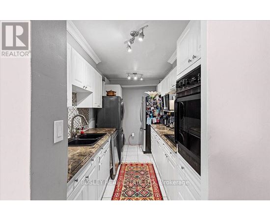 A kitchen with white cabinets and a patterned rug on the floor.