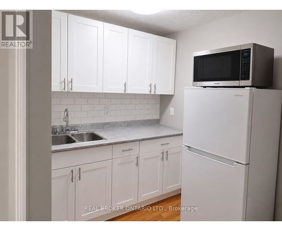 A kitchen with white cabinets and a white refrigerator.