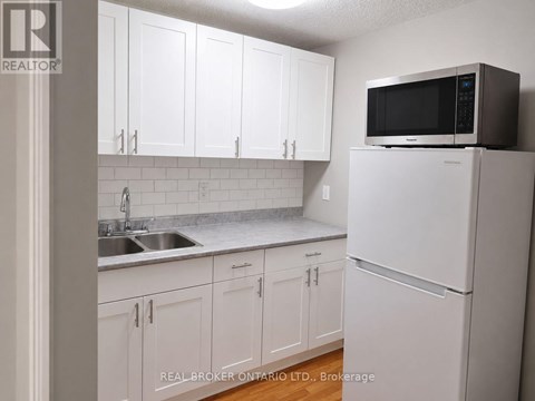 A kitchen with white cabinets and a white refrigerator.