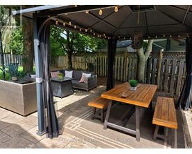 A wooden table is surrounded by chairs and a canopy.