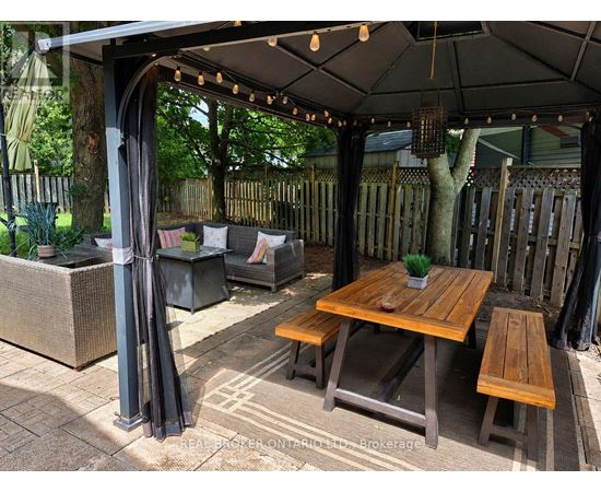 A wooden table is surrounded by chairs and a canopy.