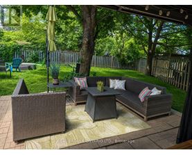 A patio with a couch, chairs, and a table with a yellow umbrella.