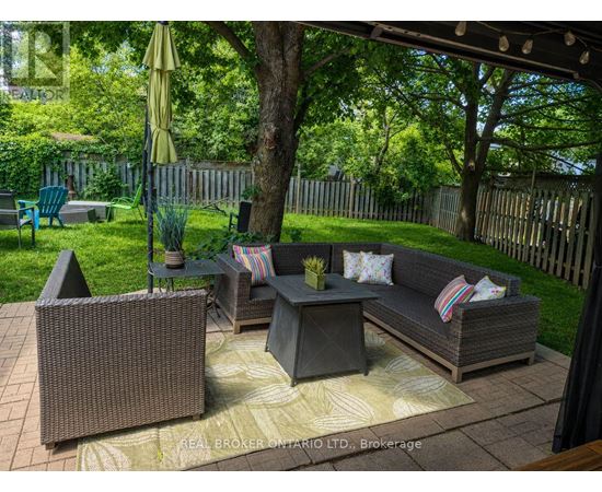 A patio with a couch, chairs, and a table with a yellow umbrella.