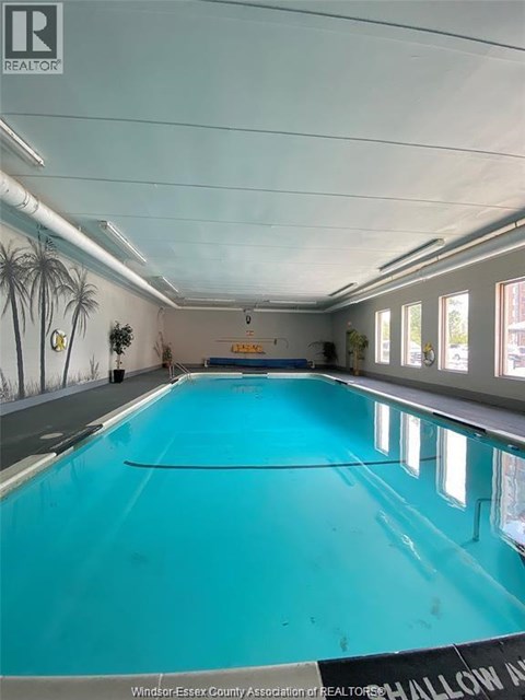 A large indoor swimming pool with a sign that says "Windsor-Essex County Association of REALTORS".