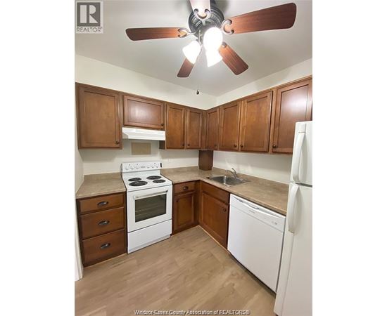 A kitchen with white appliances and wooden cabinets.