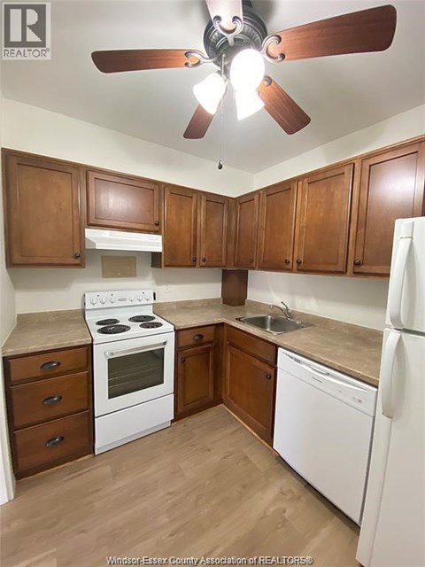 A kitchen with white appliances and wooden cabinets.
