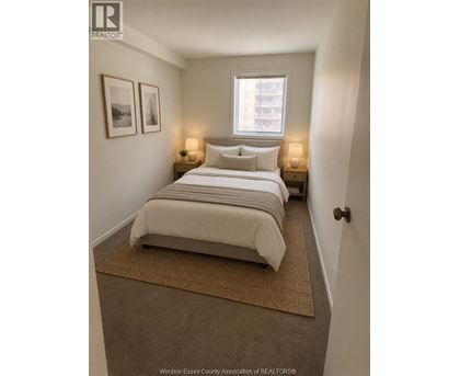 A bedroom with a bed, two nightstands with lamps, and pictures on the wall.