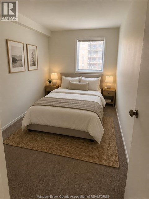 A bedroom with a bed, two nightstands with lamps, and pictures on the wall.