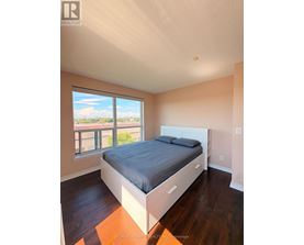 A bedroom with a large bed and a window overlooking a balcony.