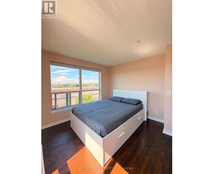 A bedroom with a large bed and a window overlooking a balcony.