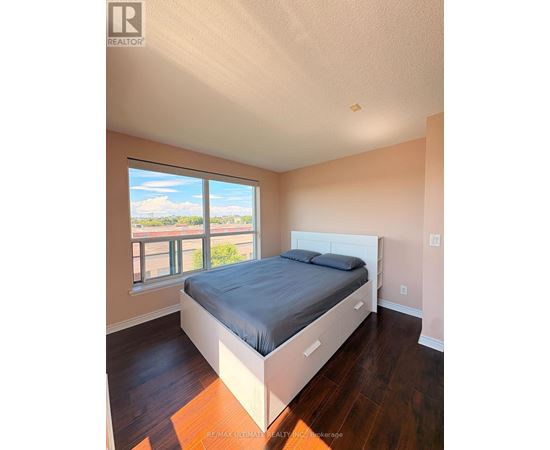 A bedroom with a large bed and a window overlooking a balcony.
