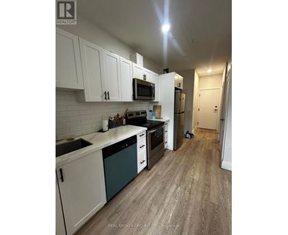 A kitchen with white cabinets and a wooden floor.