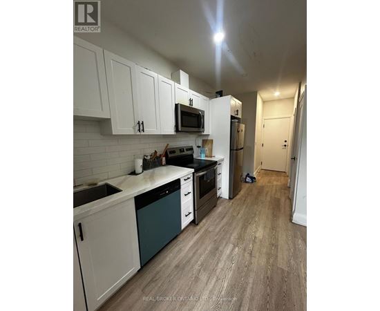 A kitchen with white cabinets and a wooden floor.