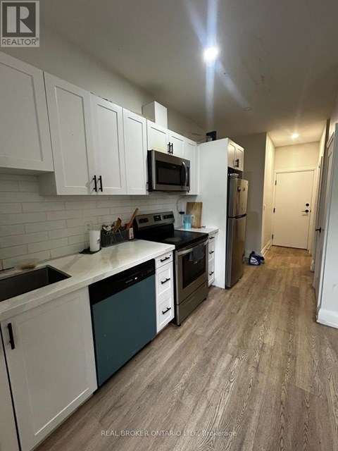 A kitchen with white cabinets and a wooden floor.