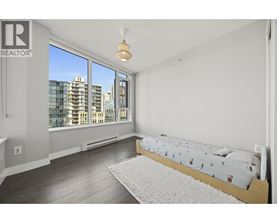 A bedroom with a large bed and a window overlooking a cityscape.