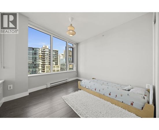 A bedroom with a large bed and a window overlooking a cityscape.