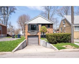 A house with a grey garage door is surrounded by a green lawn and a sidewalk.