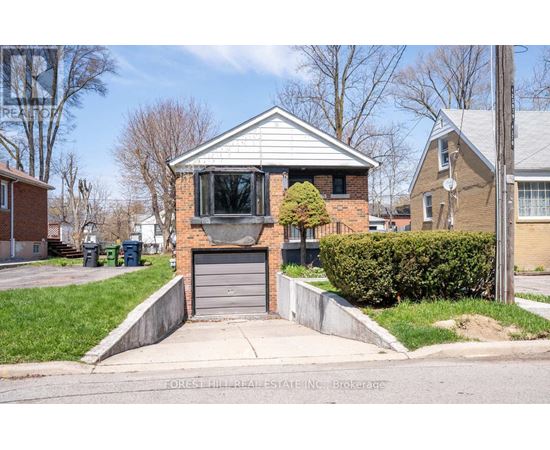 A house with a grey garage door is surrounded by a green lawn and a sidewalk.