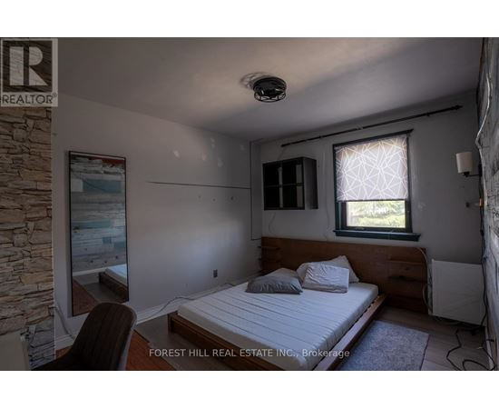 A bedroom with a bed, chair, and window.