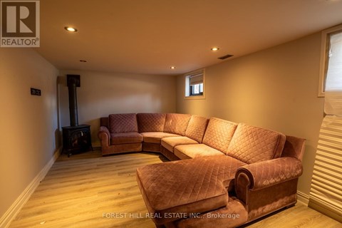A living room with a brown sofa and a wood burning stove.