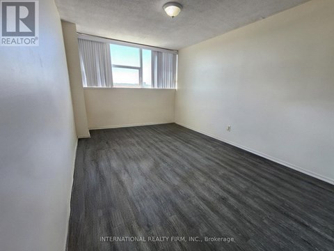 A room with a grey floor and a window with white curtains.
