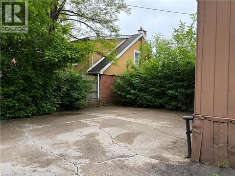 A cracked driveway leads to a house with a gate.