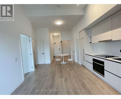 A spacious kitchen with white cabinets and a wooden floor.