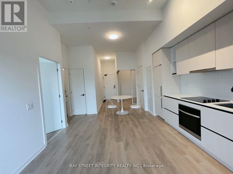 A spacious kitchen with white cabinets and a wooden floor.