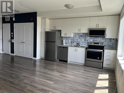 A kitchen with white cabinets and a black fridge.