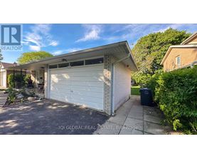 A white garage door is closed and the house is white.