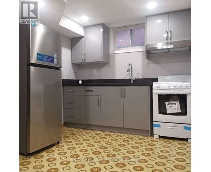 A kitchen with a refrigerator, oven, and cabinets.