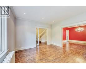 A spacious room with wood flooring and a chandelier.