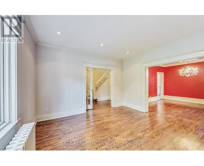 A spacious room with wood flooring and a chandelier.