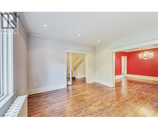 A spacious room with wood flooring and a chandelier.