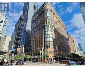 A tall building with a curved facade is located in a busy city intersection.